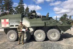 Military member in front of tank with care package